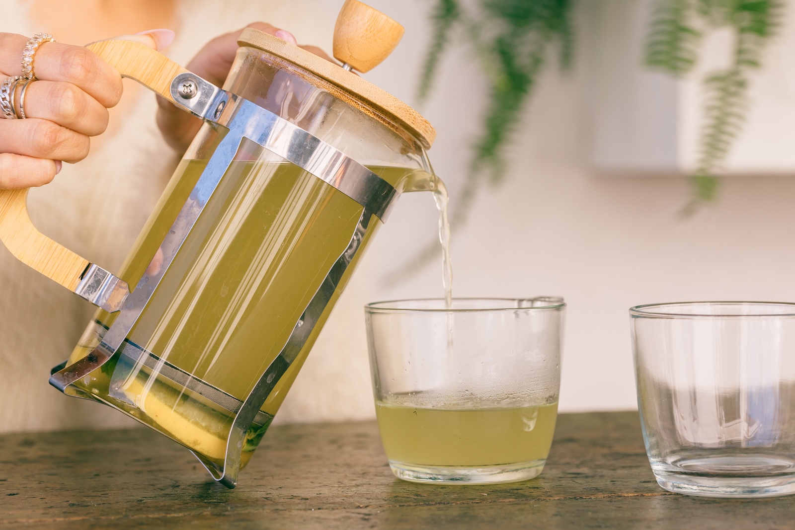 Herbal tea being poured into glasses from a french press.