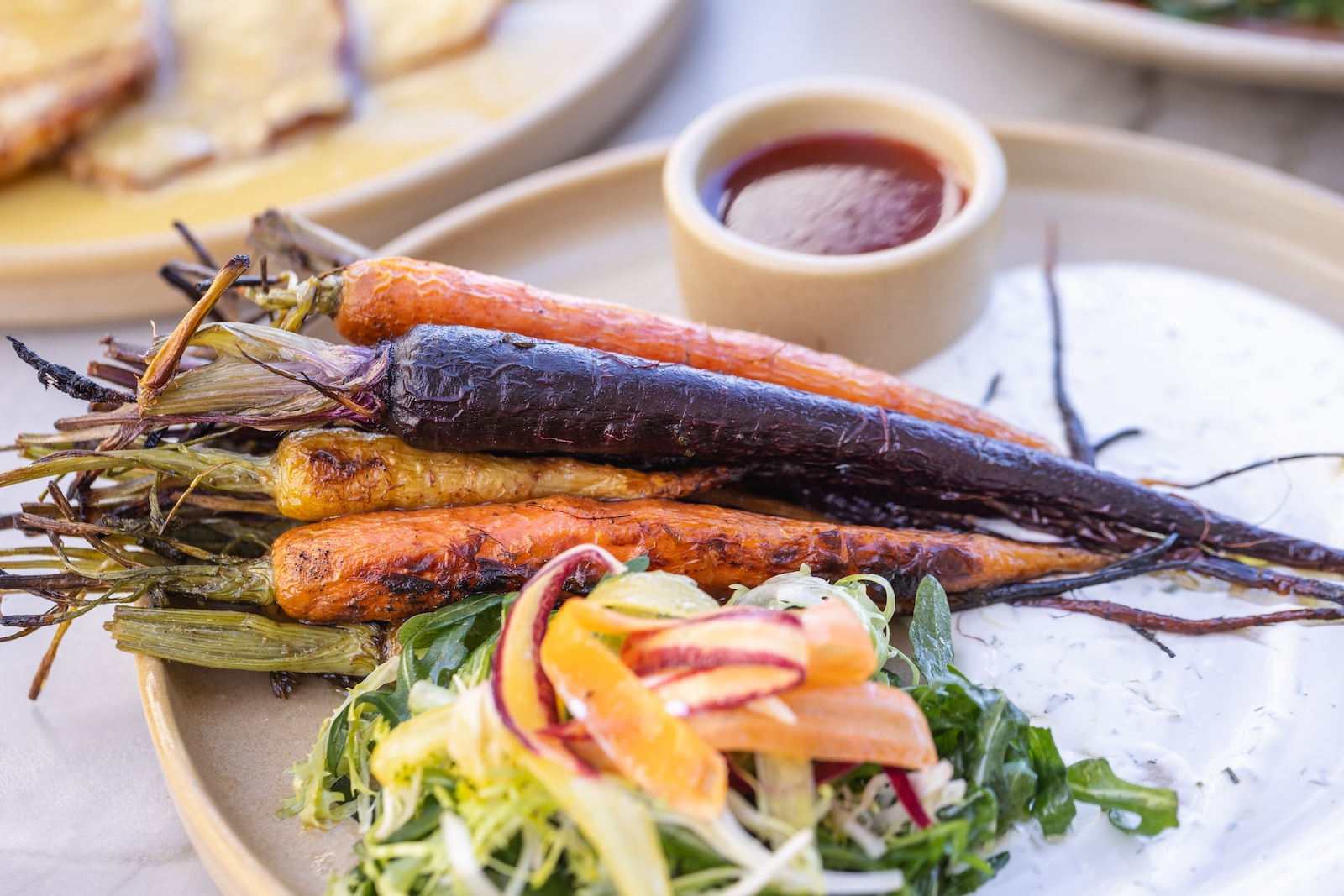 A plate of wood-fired carrots in multiple colors on a serving board.